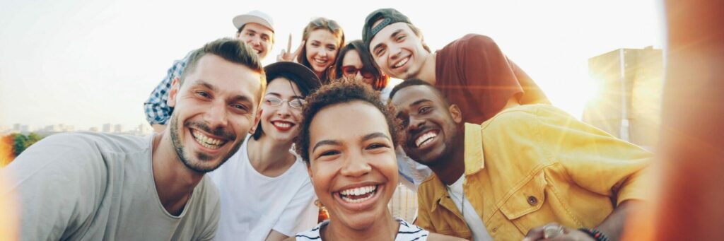 A diverse group of friends taking a joyful selfie outdoors during sunset.